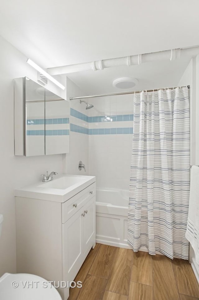 full bath with toilet, shower / bathtub combination with curtain, vanity, and wood finished floors
