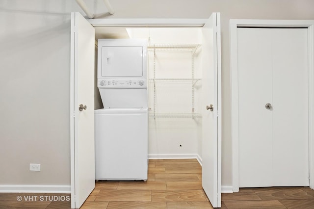 laundry room featuring baseboards, laundry area, wood tiled floor, and stacked washer and clothes dryer