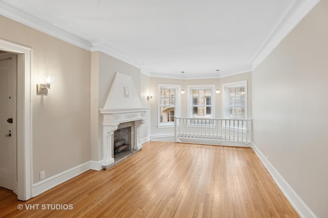 unfurnished living room featuring light wood-type flooring, baseboards, ornamental molding, and a fireplace with raised hearth