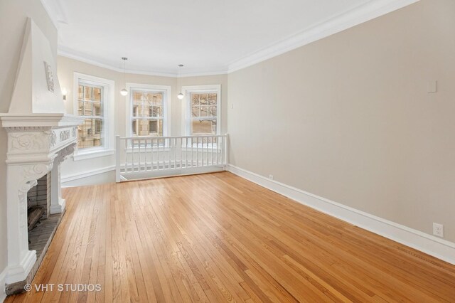 unfurnished living room with a brick fireplace, baseboards, ornamental molding, and light wood-style flooring