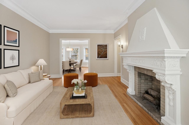 living area featuring a brick fireplace, baseboards, ornamental molding, and wood finished floors