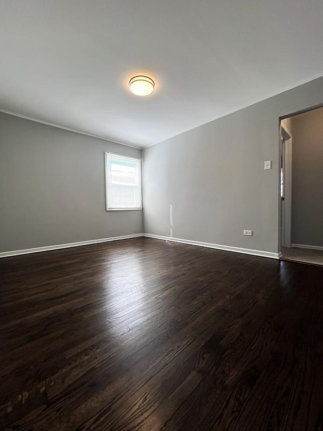 spare room with dark wood finished floors and baseboards