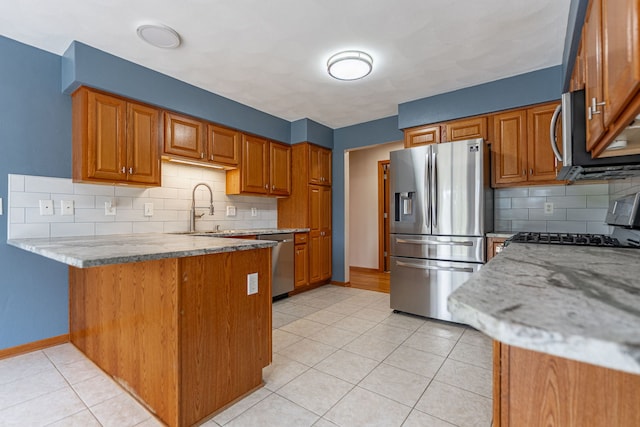 kitchen with tasteful backsplash, brown cabinetry, stainless steel appliances, and a peninsula