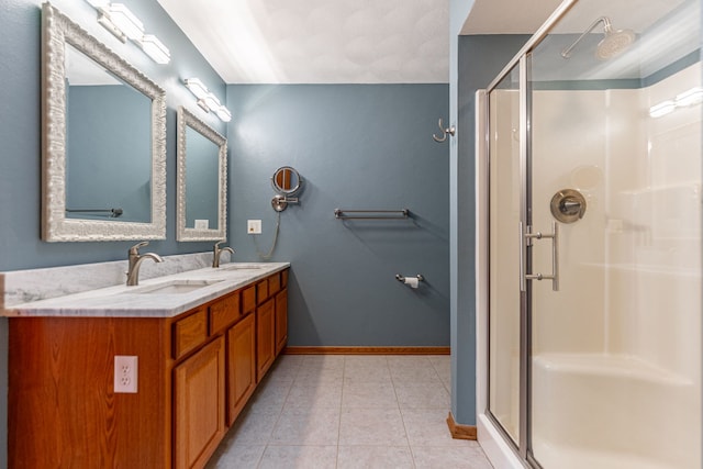 bathroom featuring baseboards, tile patterned floors, a sink, and a stall shower