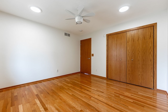 unfurnished bedroom featuring ceiling fan, light wood-style floors, baseboards, visible vents, and a closet
