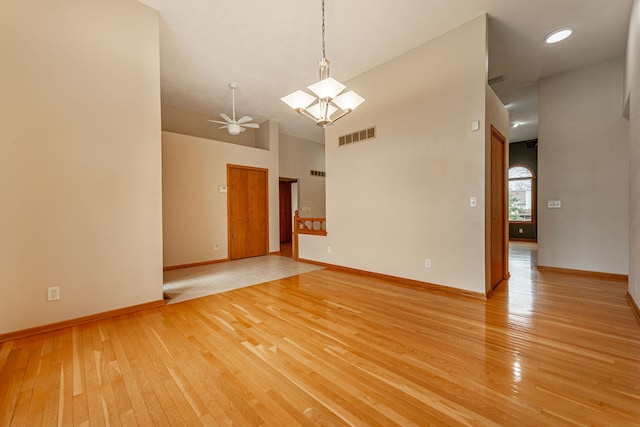 unfurnished room with baseboards, a high ceiling, light wood-style flooring, and visible vents