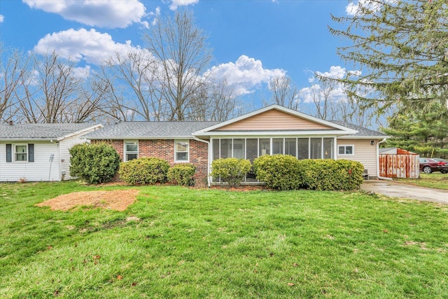 ranch-style house featuring a front yard, a sunroom, a shingled roof, and fence