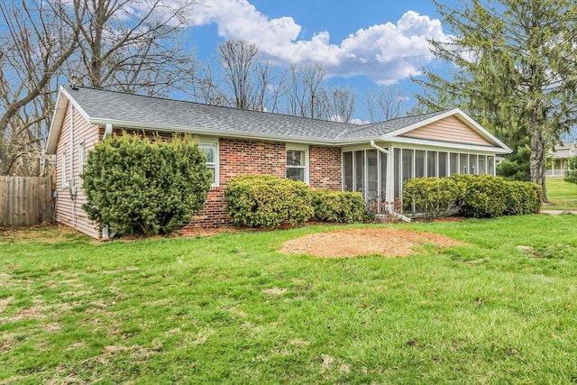 view of front of home featuring a sunroom, fence, a front yard, brick siding, and a shingled roof