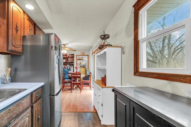 kitchen featuring light countertops, ceiling fan, wood finished floors, brown cabinets, and freestanding refrigerator