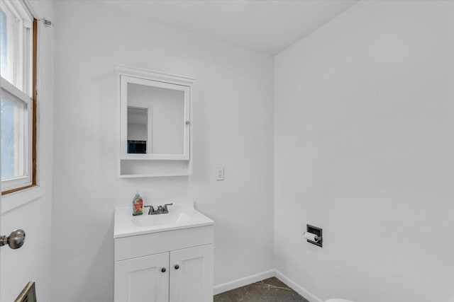 bathroom featuring vanity, baseboards, and a healthy amount of sunlight