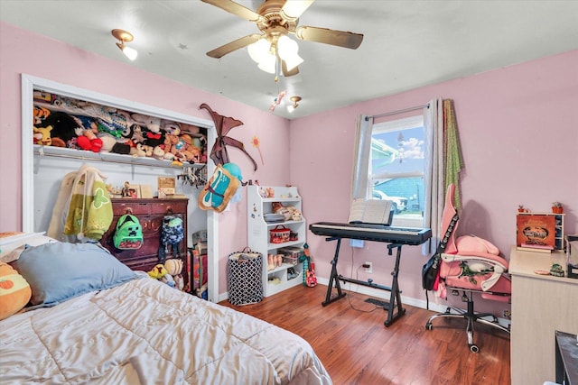 bedroom featuring baseboards, wood finished floors, and a ceiling fan