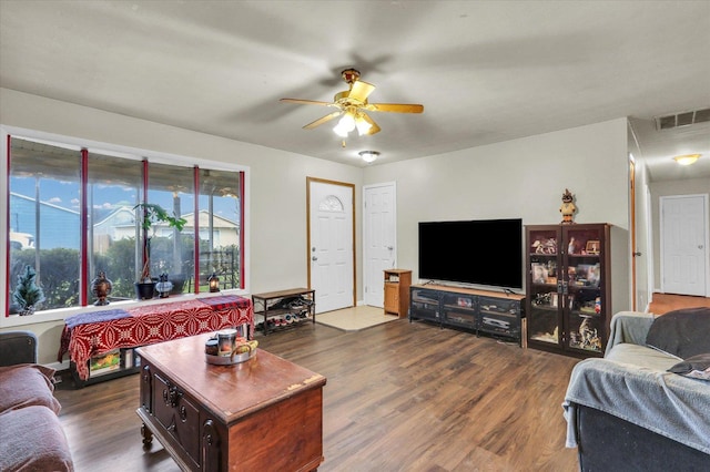 living room featuring dark wood-style flooring, visible vents, and a ceiling fan