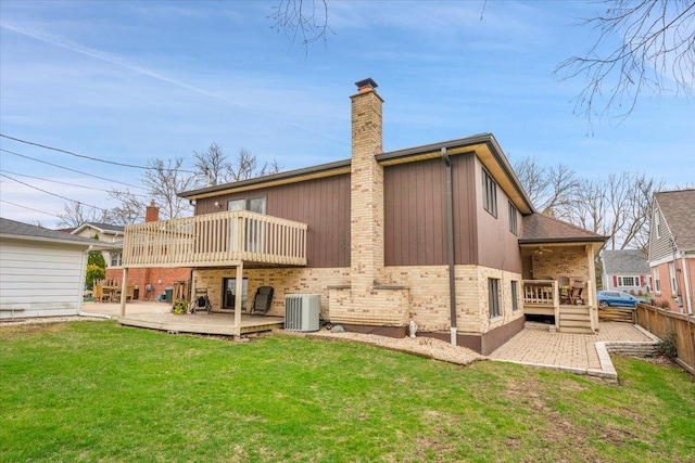 back of property featuring central AC unit, a deck, a lawn, and a chimney
