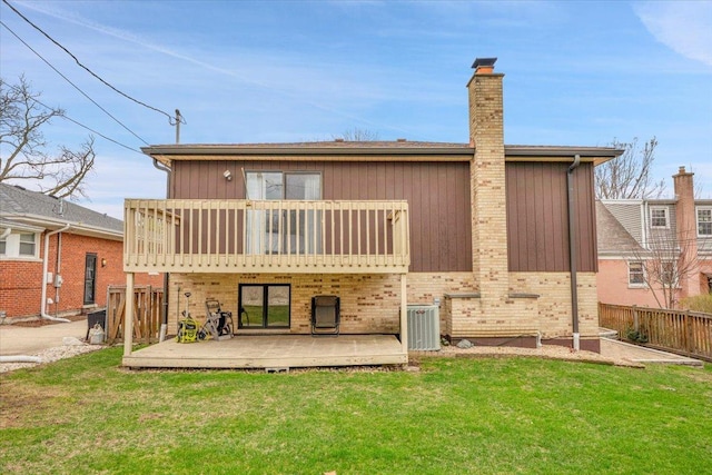 back of house featuring a chimney, cooling unit, a deck, fence, and a lawn
