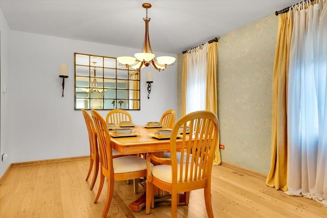 dining room with a chandelier, light wood-type flooring, wallpapered walls, and baseboards