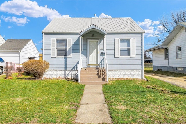 bungalow-style home featuring entry steps, a front yard, and metal roof