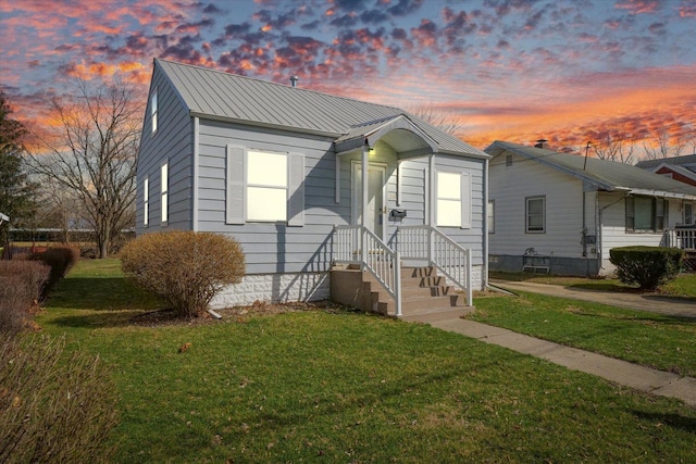 view of front facade featuring a lawn and metal roof