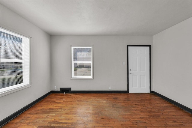 unfurnished room featuring visible vents, wood finished floors, and baseboards