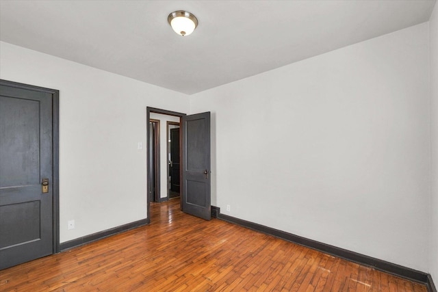 unfurnished room with hardwood / wood-style flooring and baseboards