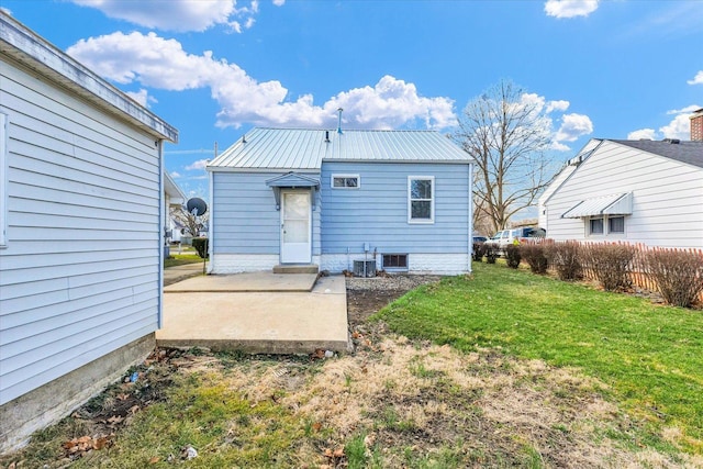 rear view of property featuring central air condition unit, a lawn, metal roof, and a patio