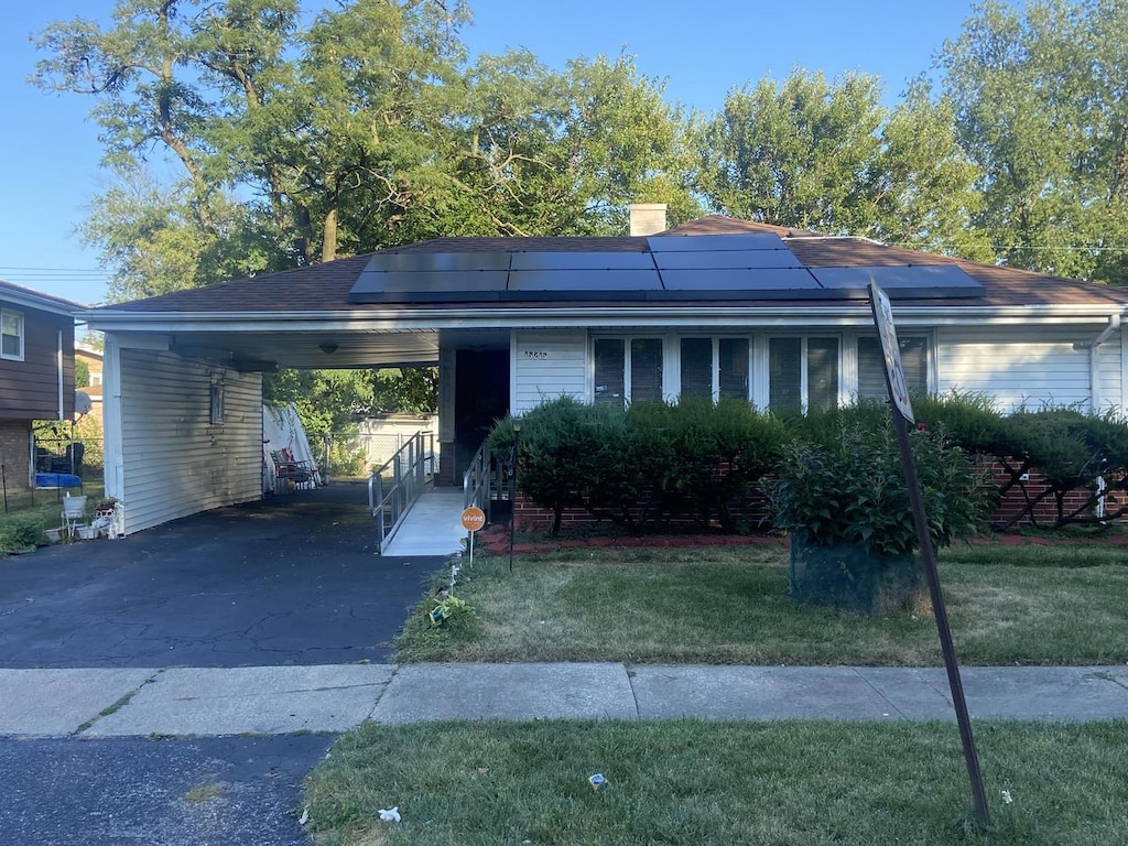 15215 Hastings Dr, Dolton, IL 60419 - view of front of house featuring a front lawn, aphalt driveway, roof mounted solar panels, a carport, and a chimney