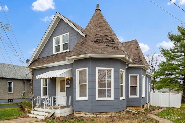 view of front facade with roof with shingles and fence