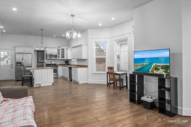 living room featuring recessed lighting, baseboards, dark wood-type flooring, and a chandelier