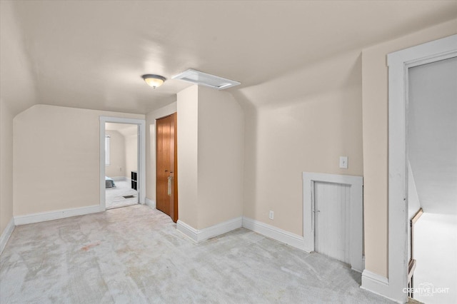 additional living space with baseboards, light colored carpet, and vaulted ceiling