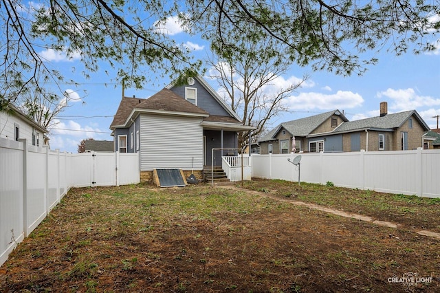 back of property with a fenced backyard and a gate