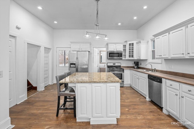 kitchen featuring a sink, appliances with stainless steel finishes, dark wood-style flooring, and a center island