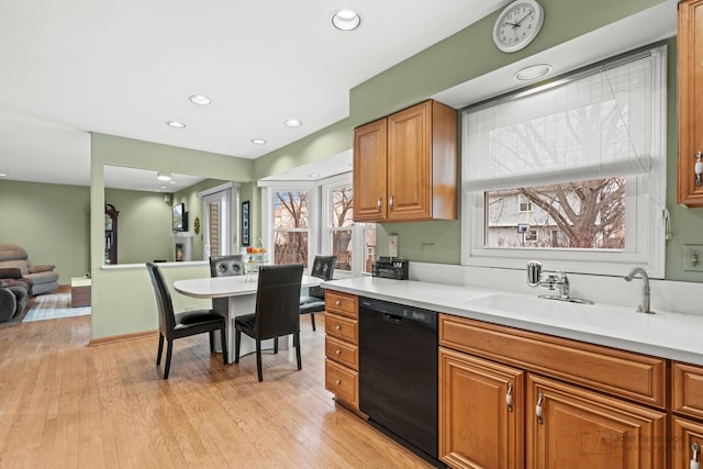 kitchen with light countertops, light wood-style floors, black dishwasher, and a sink