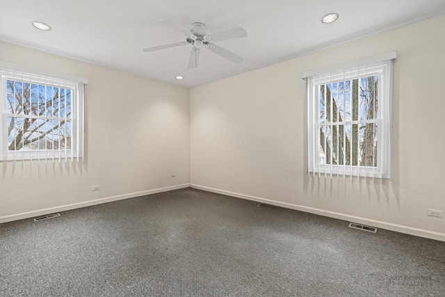 spare room with dark carpet, baseboards, and a healthy amount of sunlight