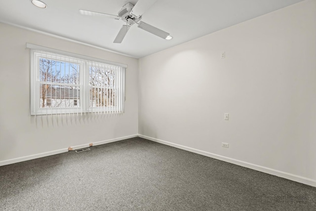spare room with visible vents, baseboards, ceiling fan, and dark colored carpet