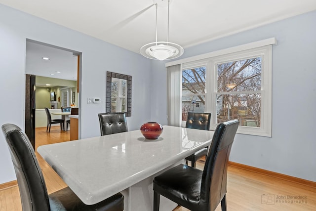 dining space featuring light wood-type flooring and baseboards