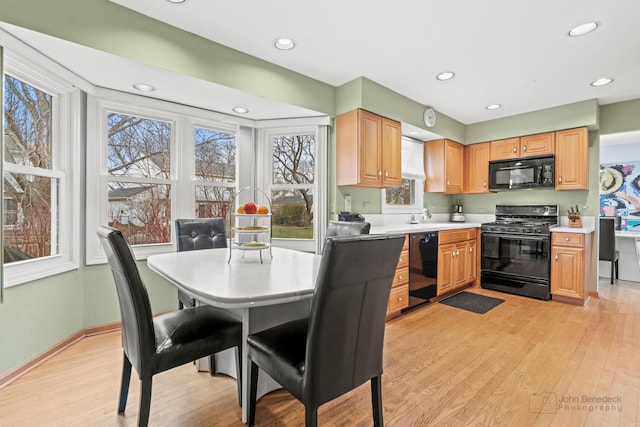 kitchen featuring black appliances, light wood-style flooring, light countertops, and baseboards