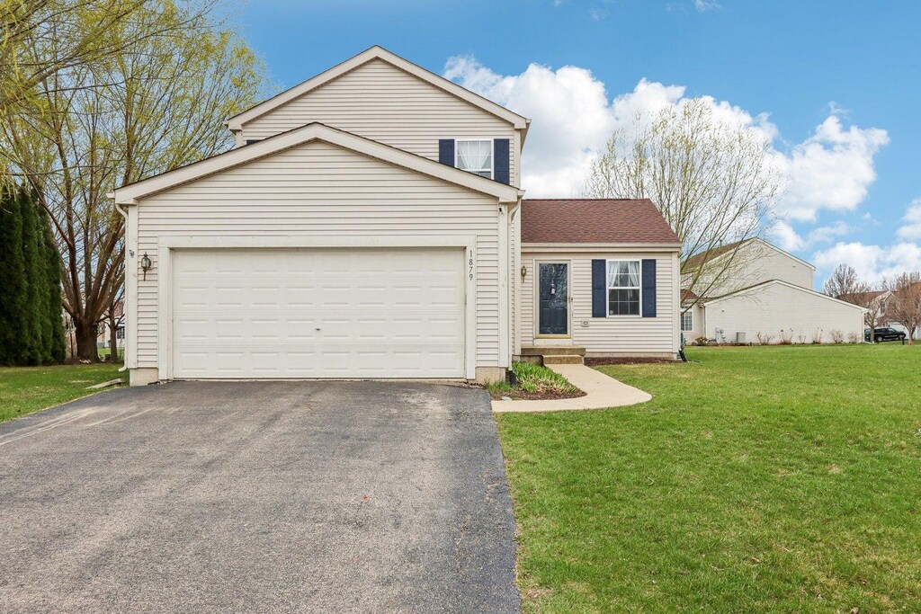 view of front of home with an attached garage, aphalt driveway, and a front yard