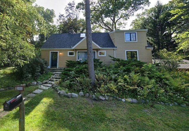 view of front of house featuring a front yard and a shingled roof