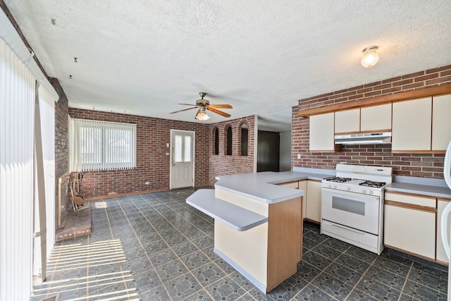 17433 Appletree Dr, Hazel Crest, IL 60429 - kitchen with white gas range oven, under cabinet range hood, brick wall, a peninsula, and light countertops