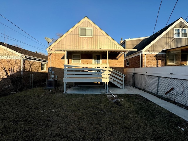 rear view of property with board and batten siding, a yard, brick siding, and a fenced backyard