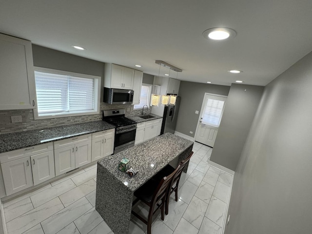 kitchen with dark stone countertops, a sink, appliances with stainless steel finishes, baseboards, and marble finish floor