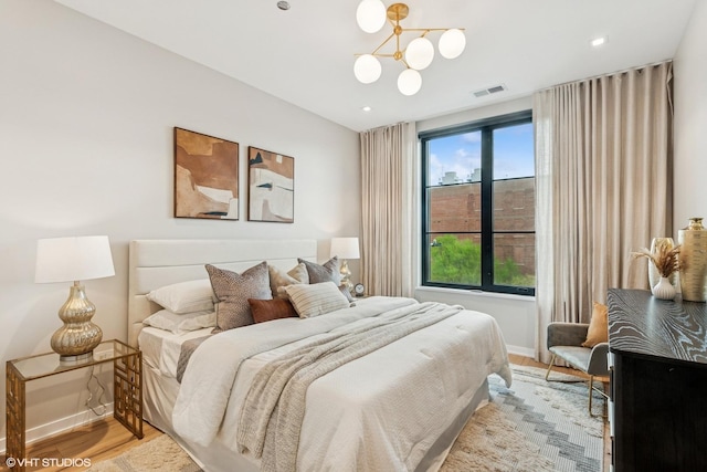 bedroom featuring baseboards, an inviting chandelier, visible vents, and light wood-type flooring