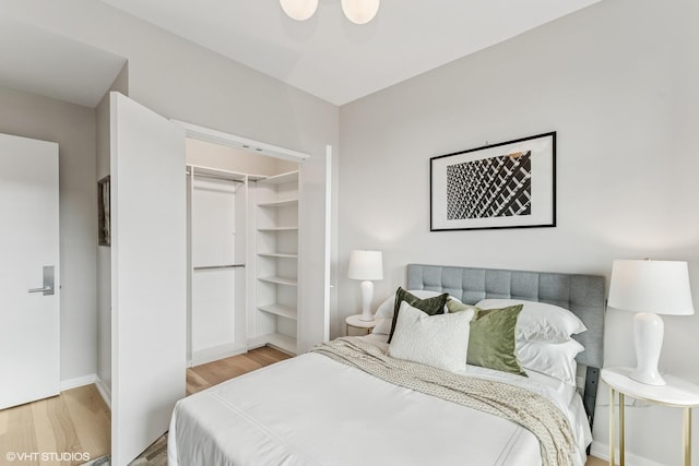 bedroom with light wood-style flooring, baseboards, and a closet