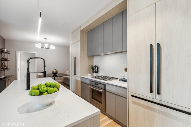 kitchen with modern cabinets, gray cabinets, an inviting chandelier, stainless steel appliances, and decorative light fixtures