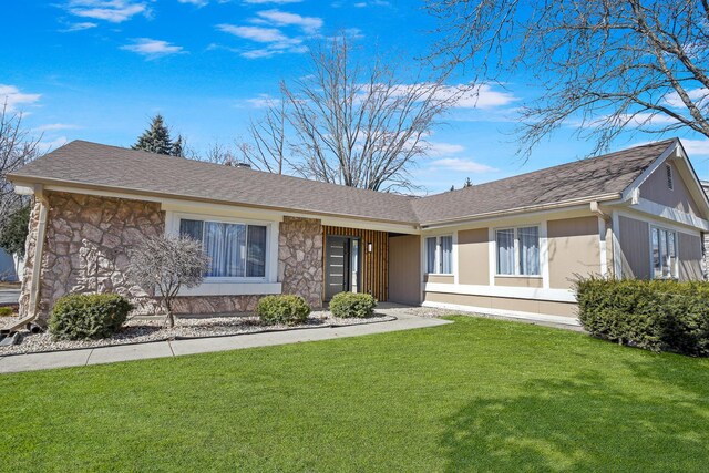 ranch-style house with a front lawn, stone siding, and a shingled roof
