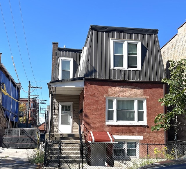 view of front of house featuring entry steps, a gate, mansard roof, a fenced front yard, and brick siding