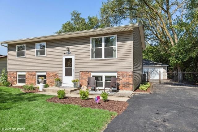 split foyer home featuring brick siding, a patio, an outdoor structure, and a front yard