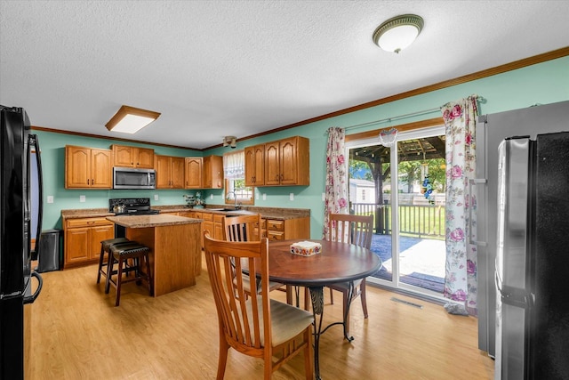 3504 Royal Oak Ct, Champaign, IL 61822 - kitchen featuring appliances with stainless steel finishes, ornamental molding, a textured ceiling, light wood-style floors, and plenty of natural light