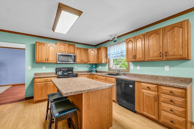3504 Royal Oak Ct, Champaign, IL 61822 - kitchen featuring black appliances, crown molding, a breakfast bar, light wood-type flooring, and a center island