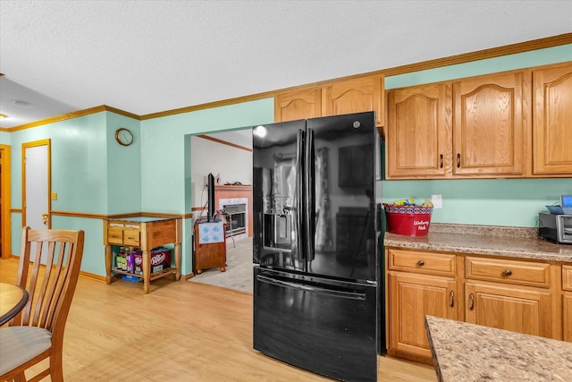 3504 Royal Oak Ct, Champaign, IL 61822 - kitchen featuring black refrigerator with ice dispenser, light wood finished floors, ornamental molding, light countertops, and a tiled fireplace