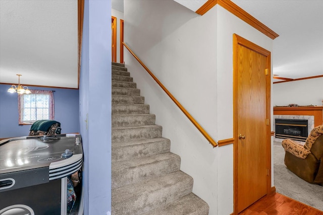 3504 Royal Oak Ct, Champaign, IL 61822 - stairway featuring crown molding, wood finished floors, a fireplace, and a chandelier